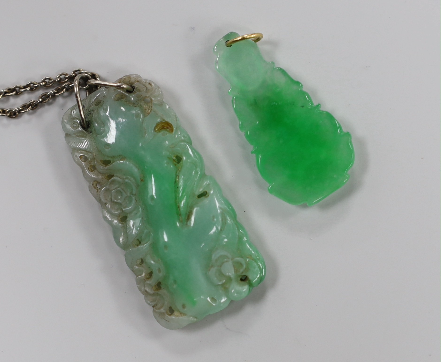 Two carved jade pendants, largest 47mm on a white metal chain.